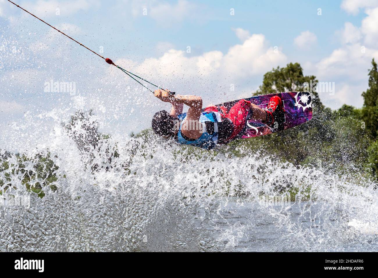 Junge aktive Profisportlerin, die auf dem Wakeboard in der Luft springt, Wassersport im Fluss Stockfoto