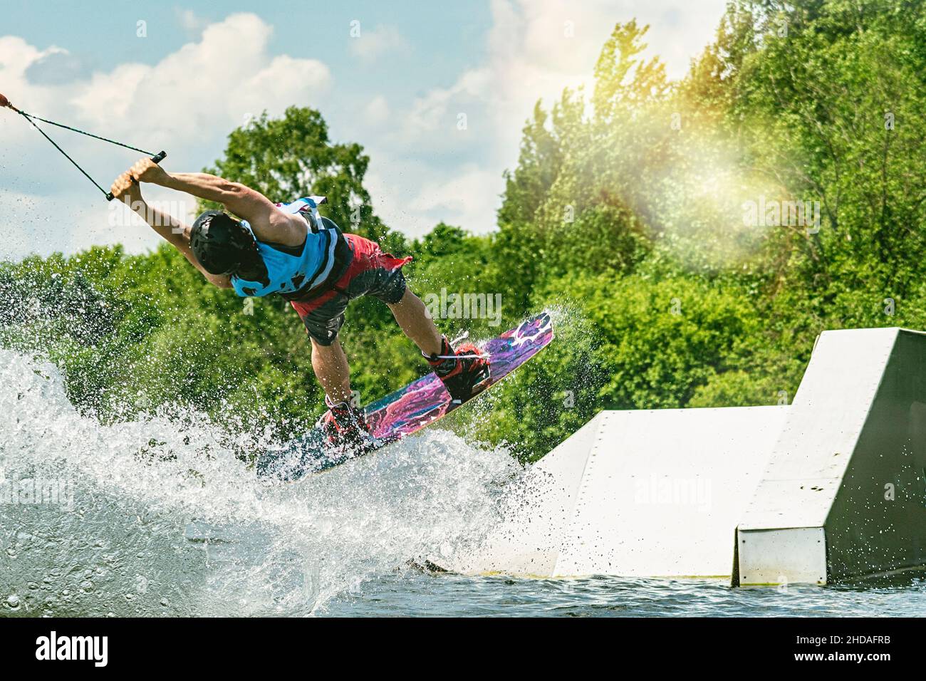 Junge aktive Profisportlerin, die auf dem Wakeboard in der Luft springt, Wassersport im Fluss Stockfoto