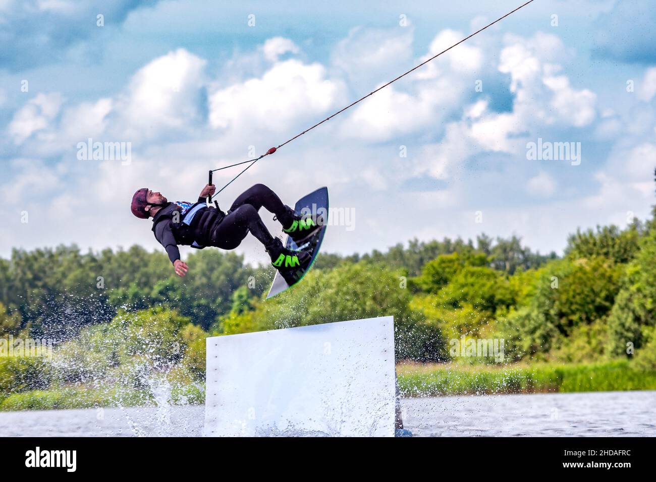 Junge aktive Profisportlerin, die auf dem Wakeboard in der Luft springt, Wassersport im Fluss Stockfoto