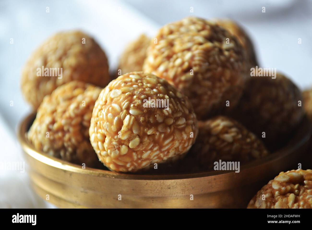 Nahaufnahme eines gezackelten Sesams/Til Laddu/Laddoo in einem Messinggerät/urli/Makar Sankranti/Indien Stockfoto