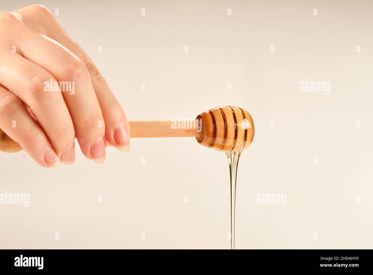 Dipper mit Honig in Frauenhand. Platz für Text oder Design. Stockfoto