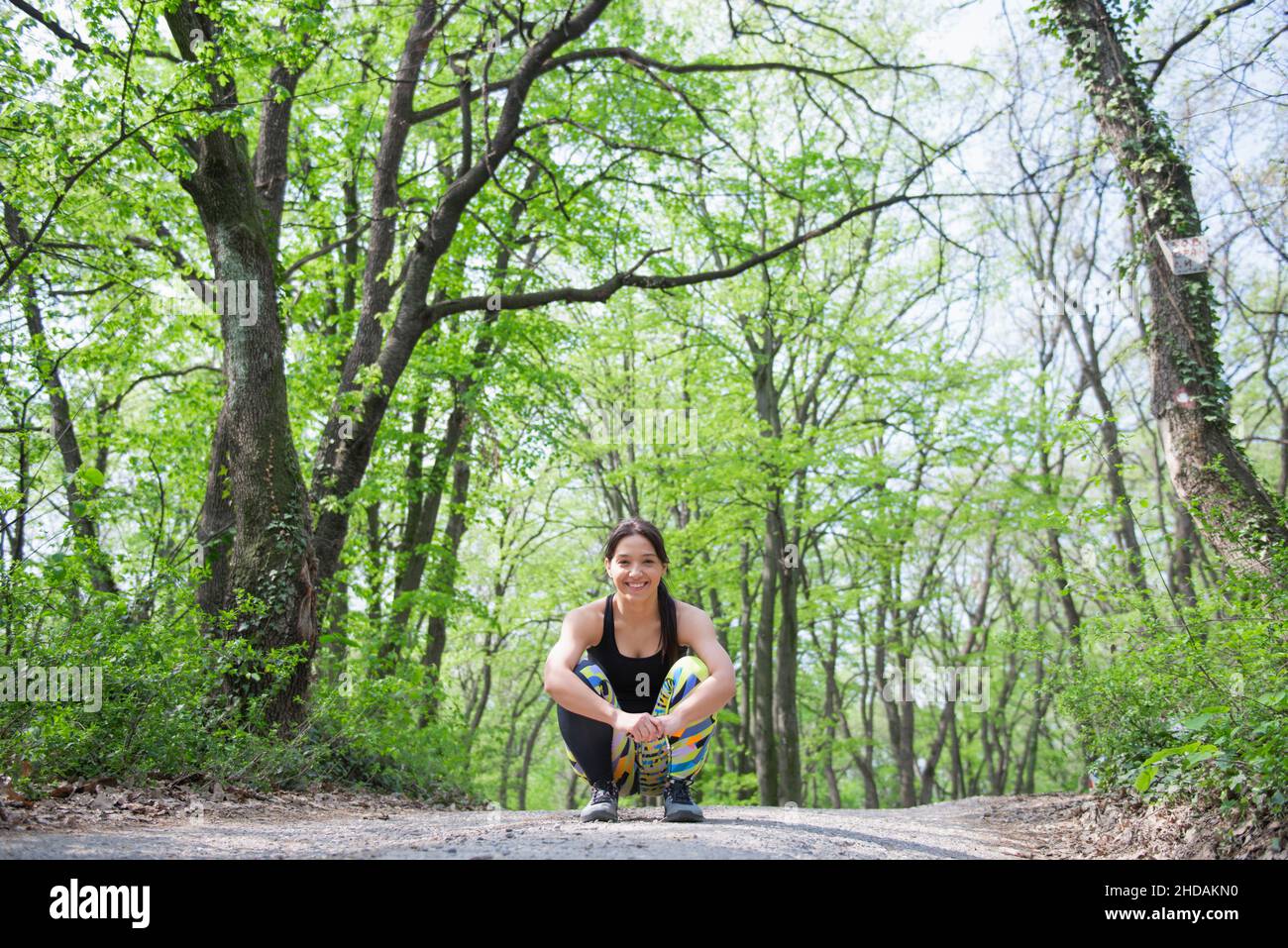 Entspannte und fröhliche Athletinnen, die ihr Training am Frühlingsmorgen im Wald genießt Stockfoto