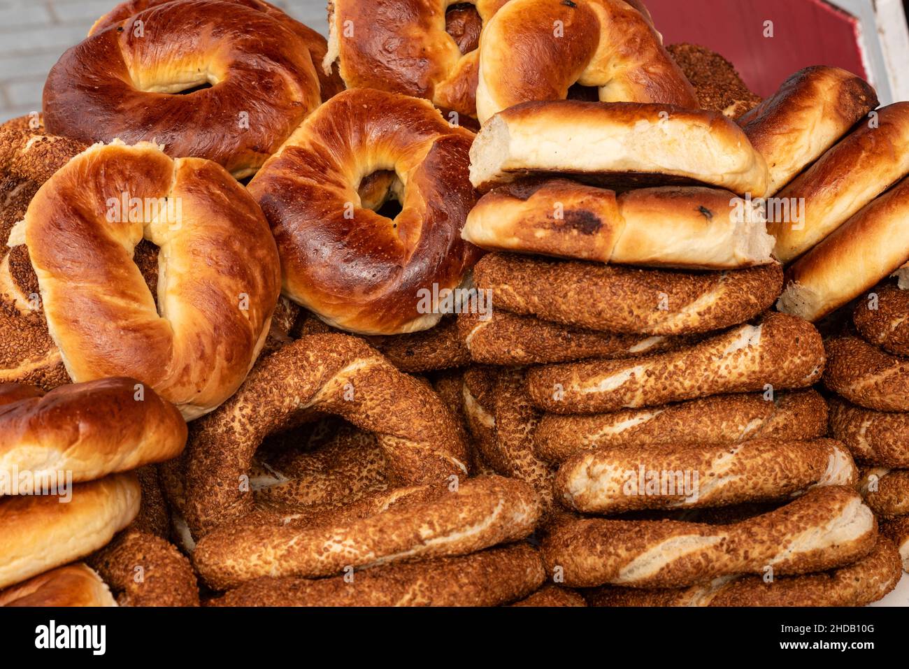 Traditionelle türkische Simit- und Sticky-Brötchen zum Verkauf bei einem Straßenhändler, beliebtes Street Food in Istanbul, Türkei. Stockfoto