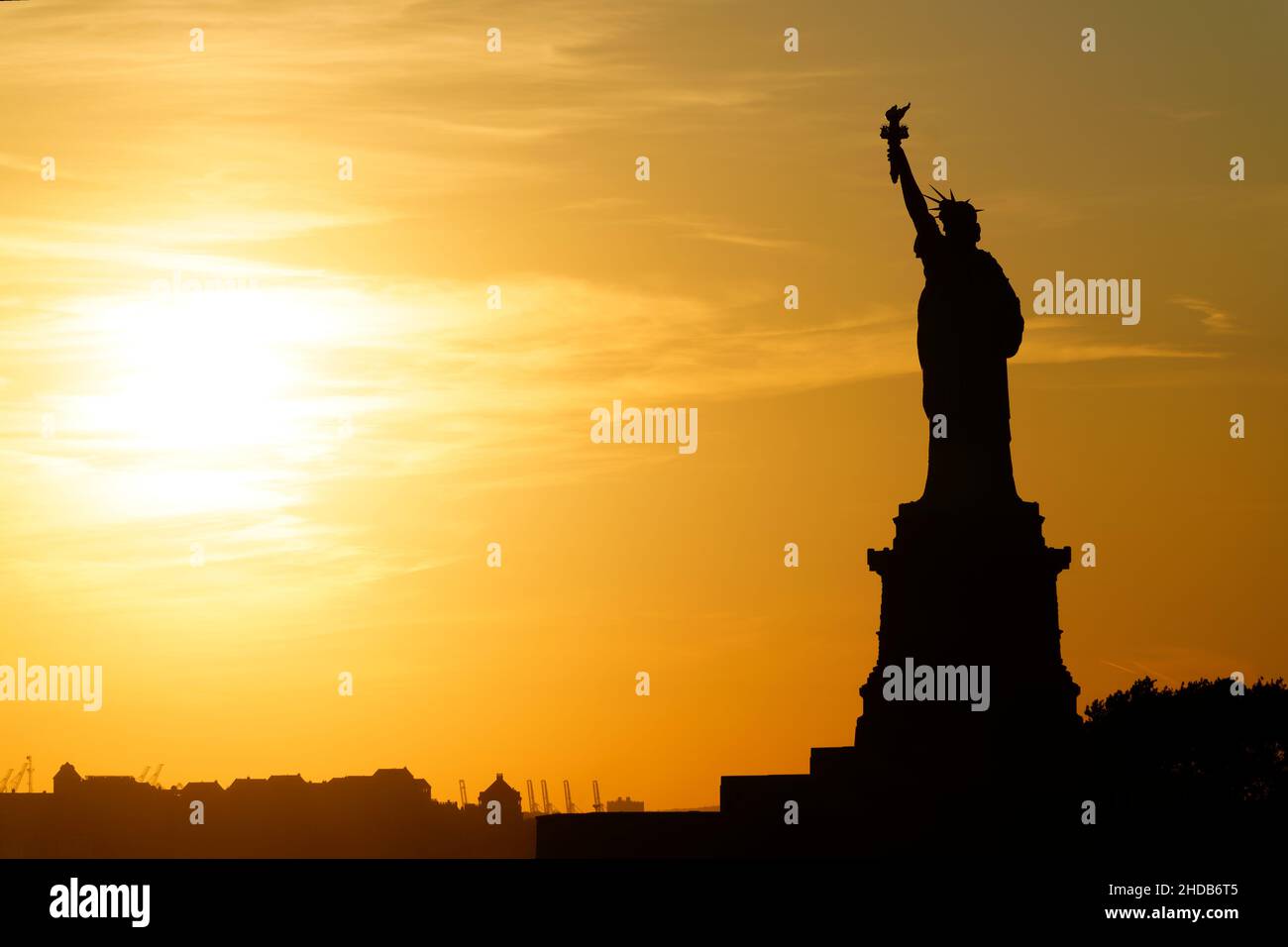 Die Statue von Libery badet in goldenem Licht, während sie den Sonnenuntergang beobachtet. Stockfoto