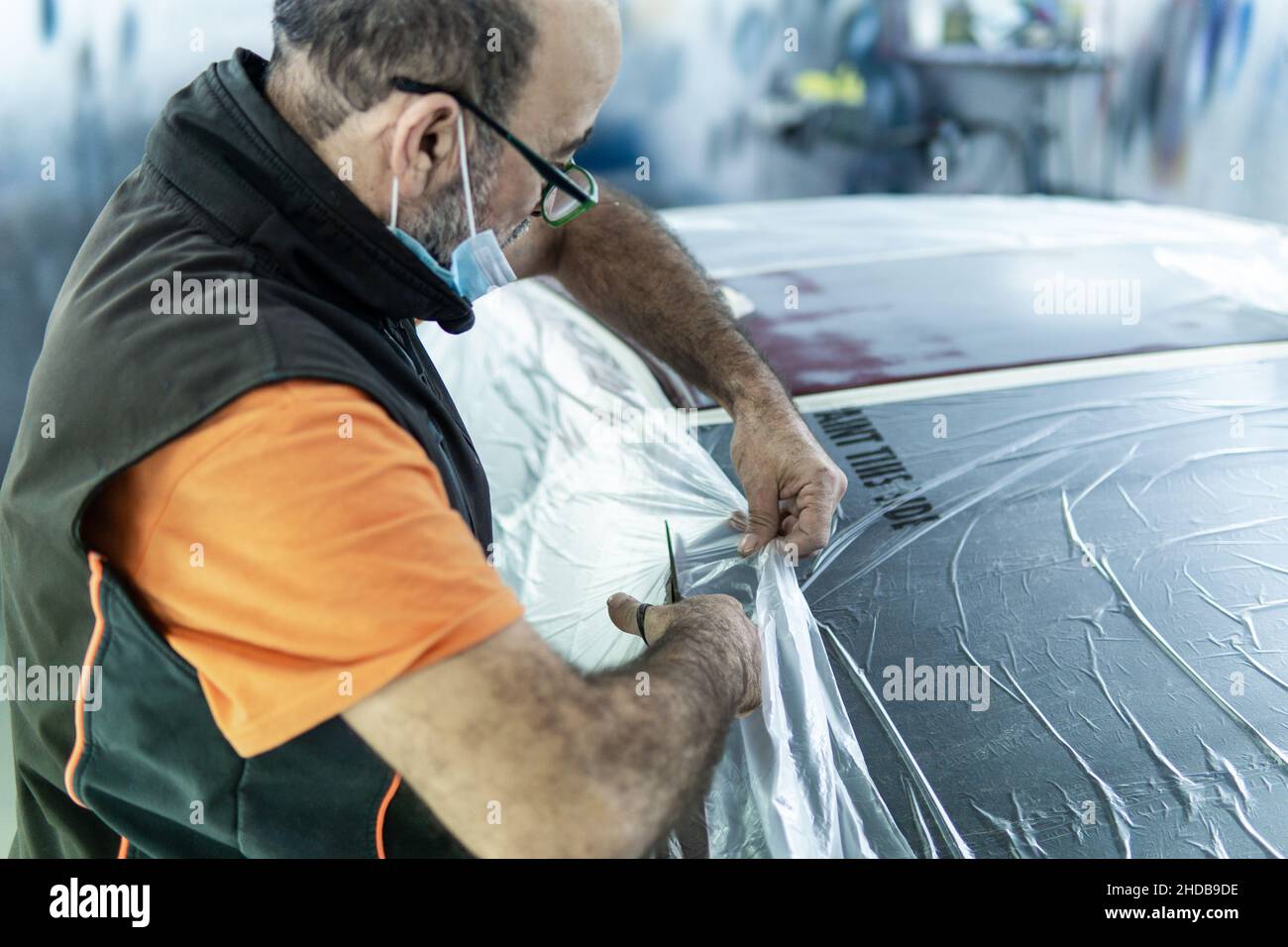 Auto Mechaniker ein Auto in einer Garage für die Lackierung vorbereiten. Die Kanten eines Autos in der Werkstatt schützen Stockfoto