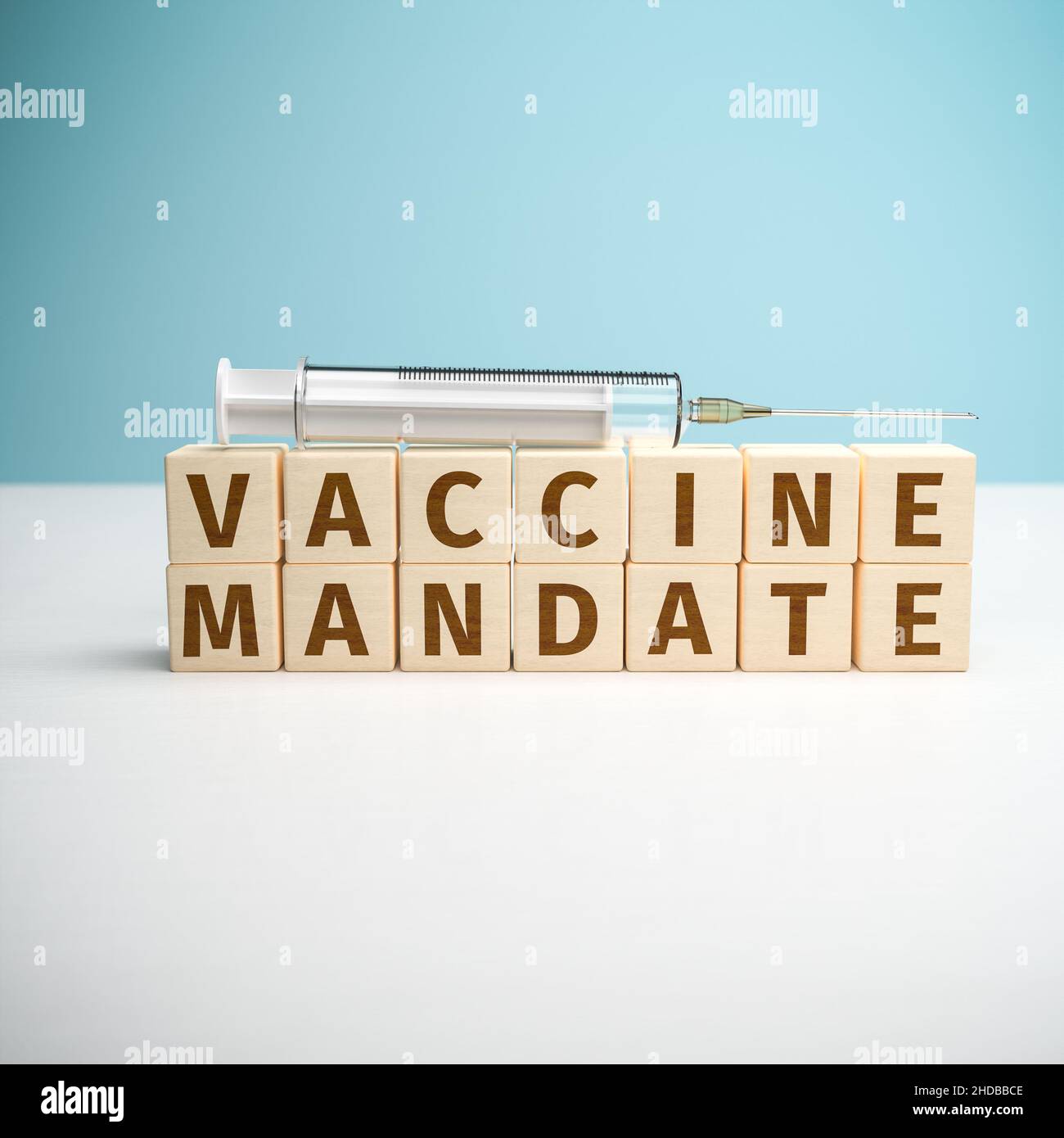 Die Worte „Impfauftrag“, die aus Buchstaben auf Holzwürfeln aufgebaut wurden. Eine Spritze auf der Oberseite. Stockfoto