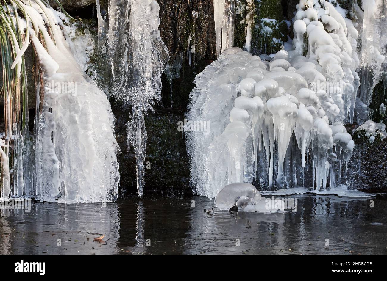 Gefrorener Wasserfall mit abstrakten Formen von Eiszapfen und Schnee im Winter, Favorite Palace Garten, Rastatt, Deutschland Stockfoto