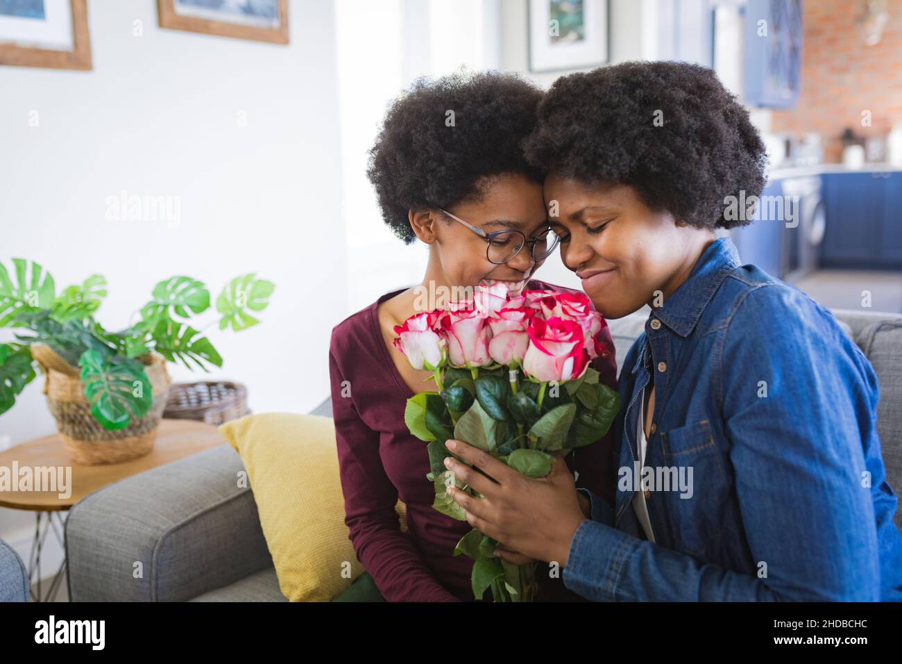 Lächelnde Mutter und Tochter mit frischem Rosenstrauß zum Geburtstag zu Hause Stockfoto