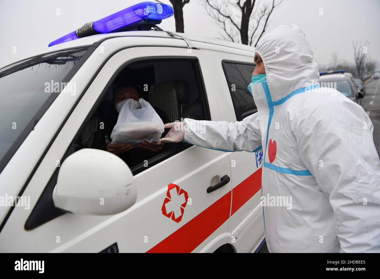 (220105) -- XI'AN, 5. Januar 2022 (Xinhua) -- der Freiwillige Chang Lin liefert einem Krankenwagen-Fahrer im Bezirk Yanta in Xi'an, nordwestlich der chinesischen Provinz Shaanxi, Lebensmittel, am 4. Januar 2022. Deshan, eine Gemeinschaftsküche im Bezirk Yanta von Xi'an, wurde als „krebsbekämpfende Küche“ geführt und bietet Krebspatienten und ihren Familien die Möglichkeit, Mahlzeiten zuzubereiten. Xu Kai, der Gründer der Gemeinschaftsküche, verwandelte diese „krebsbekämpfende Küche“ in eine „Kampf-gegen-Epidemie-Küche“, nachdem die Stadt vor kurzem vom Wiederaufleben des COVID-19 getroffen wurde. Bisher haben sich mehr als 30 Freiwillige der Lebensmittelzustellung angeschlossen Stockfoto