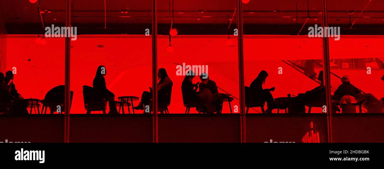 Malerischer Blick auf die Menschen, die in einem Café mit roten Lichtern herumhängen Stockfoto