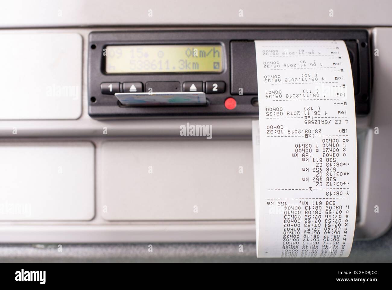 Digitaler Fahrtenschreiber mit aufgedruckten Zeitaufzeichnungen und zur Hälfte eingesteckter Fahrerkarte. Stockfoto