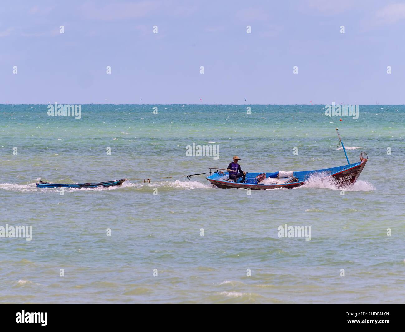Traditionelles Fischerboot, das ein kleineres Boot vor der Küste von Map Ta in der Provinz Rayong in Thailand abschleppt. Stockfoto