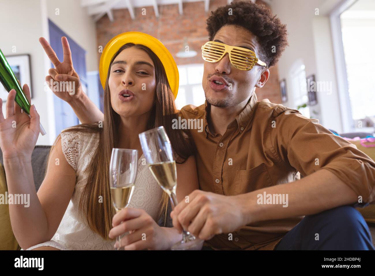 Portrait eines glücklichen Biracial-Paares, das zu Hause eine Party mit Sektflöten genießt Stockfoto