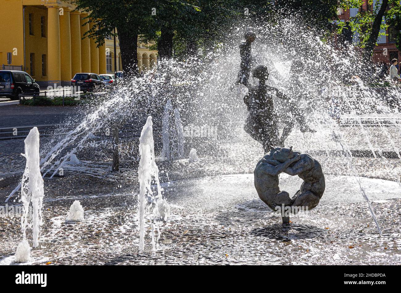 Hansestadt Rostock, Mecklenburg-Vorpommern, Deutschland: Urbane Szene am Brunnen der Lebensfreude auf dem Universitätsplatz im Gegenlicht; der Brunnen Stockfoto