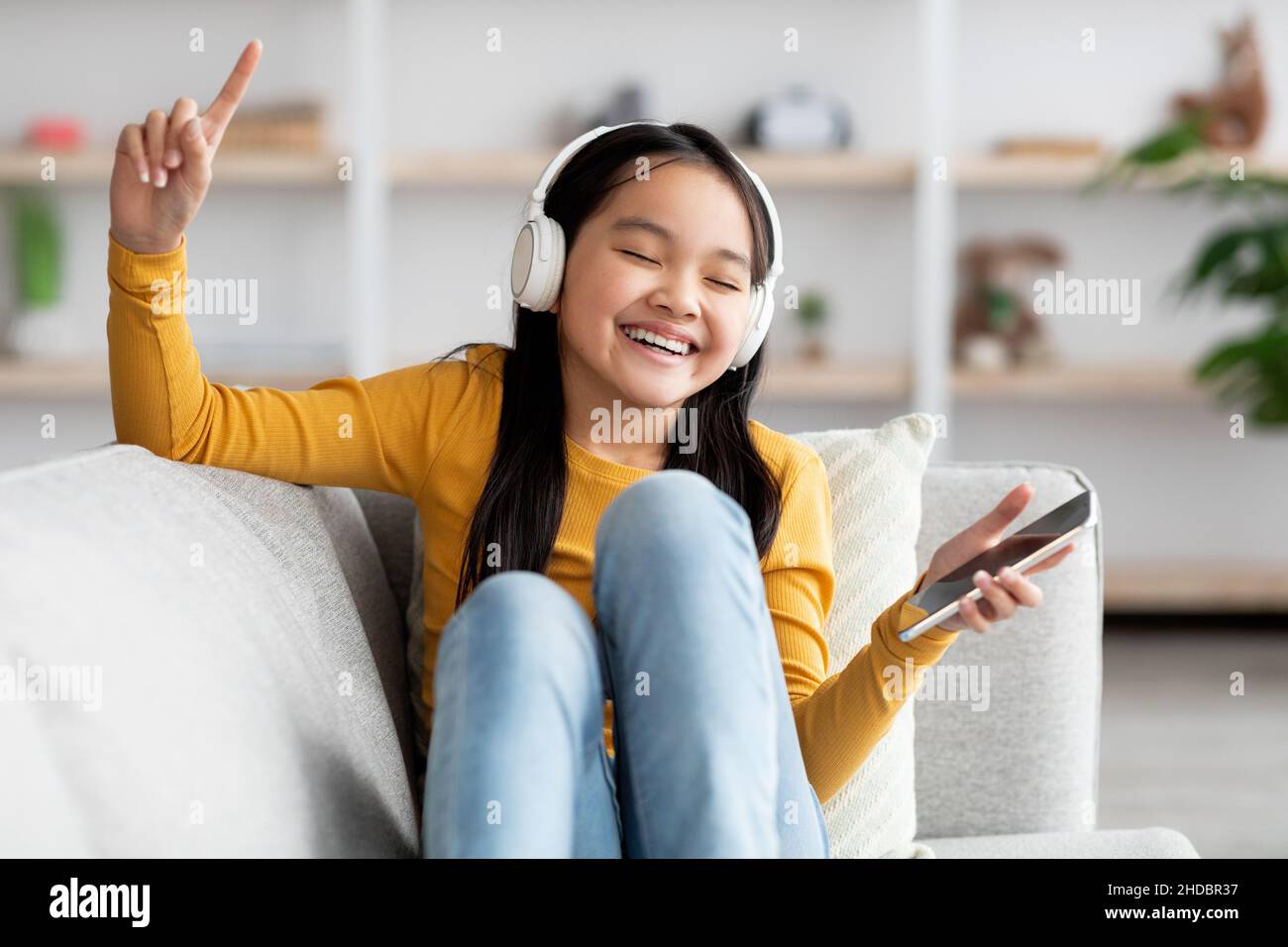 Fröhliches chinesisches Kind, das Musik auf dem Cellpohne hört Stockfoto