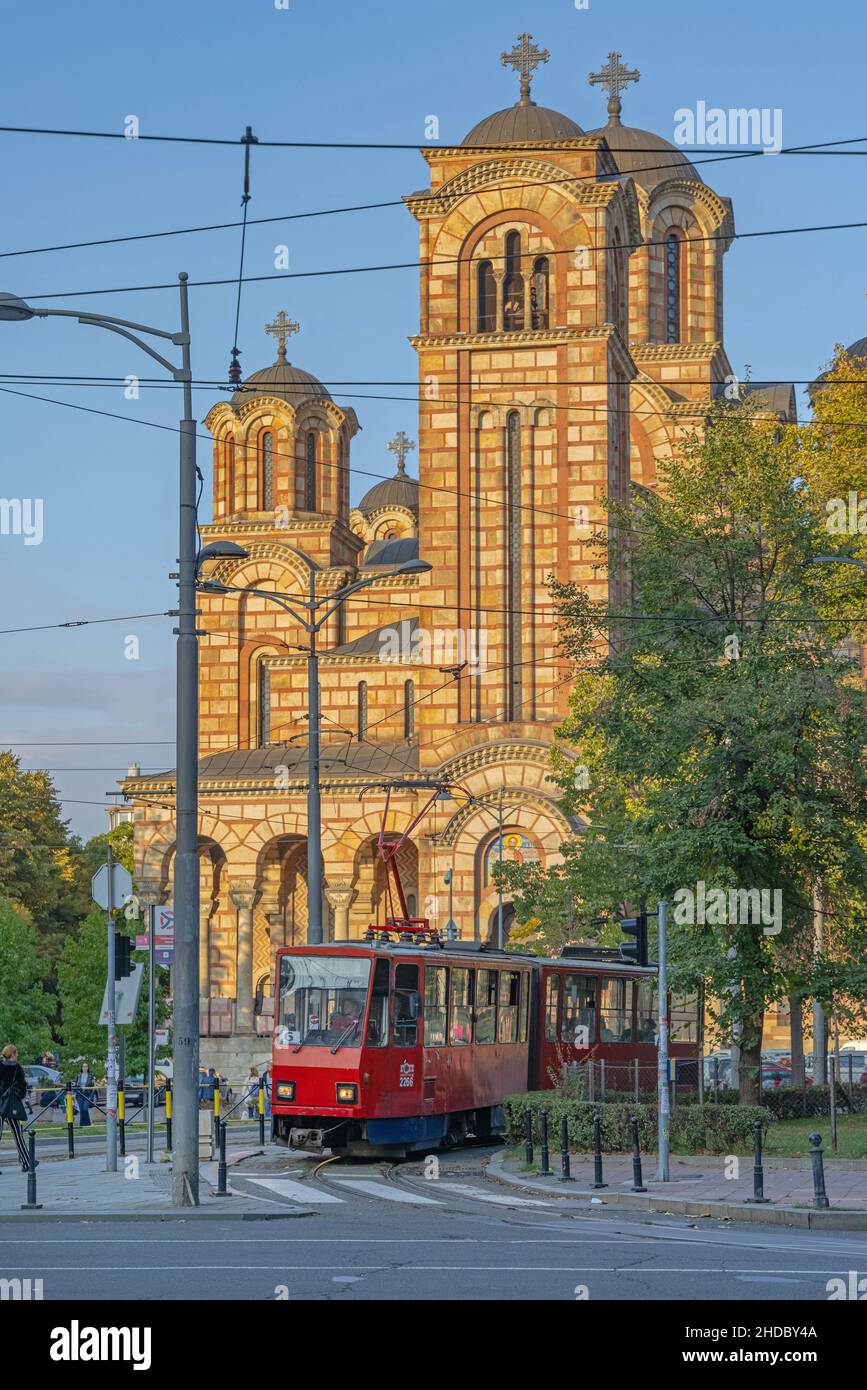Belgrad, Serbien - 01. Oktober 2021: Rote Straßenbahn vor der Orthodoxen Kirche St. Marko Herbstlicher sonniger Nachmittag. Stockfoto