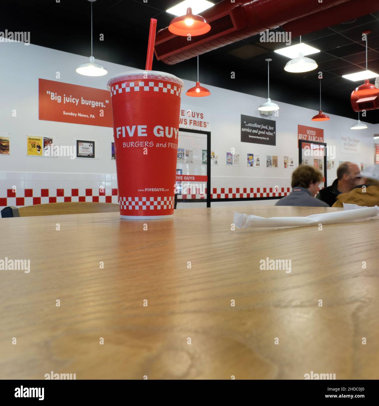 Fünf Burgers und Fries trinken einen Becher auf einem Tisch im Hamburger Restaurant; Red Soda oder Softdrink-Becher mit Stroh. Stockfoto