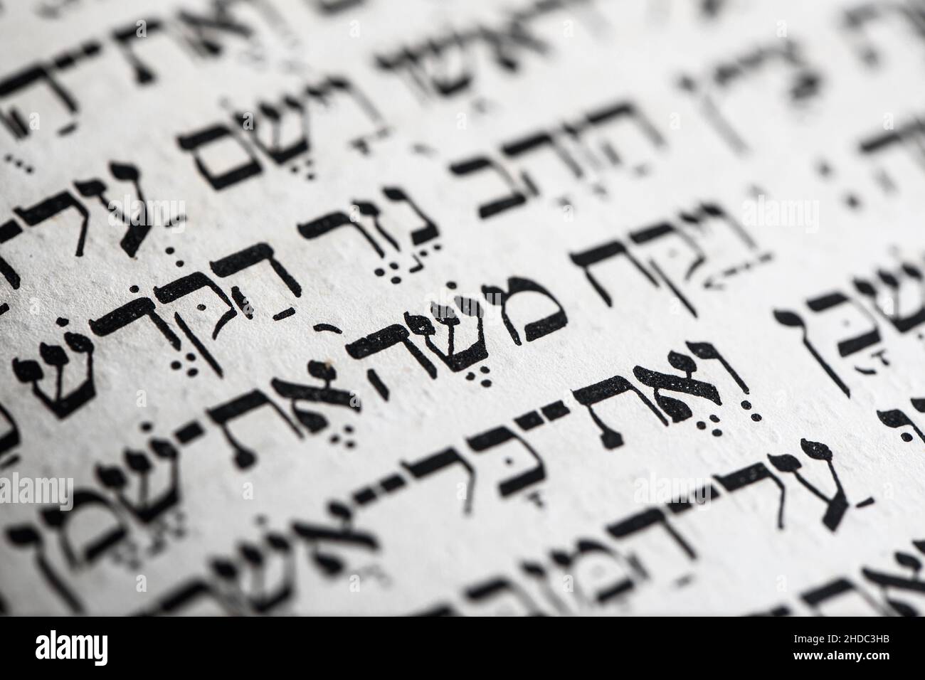 Nahaufnahme des hebräischen Wortes auf der Tora-Seite, die auf englisch mit Moses übersetzt wird, Namensprophet im Judentum, Anführer der Israeliten und Gesetzgeber. Selektiver Fokus Stockfoto