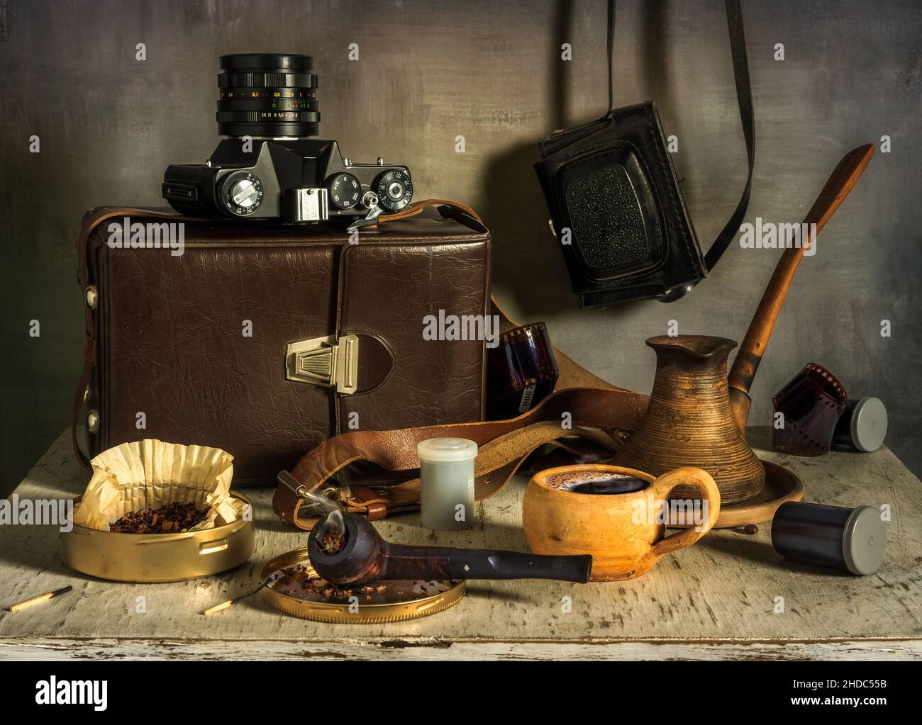Eine Tasse aromatischen Kaffee. Eine Rauchpfeife und eine Kiste Tabak. Alte Filmkameras, Fotofilm, Lederetui für Fotoausrüstung. Altes Foto Stockfoto