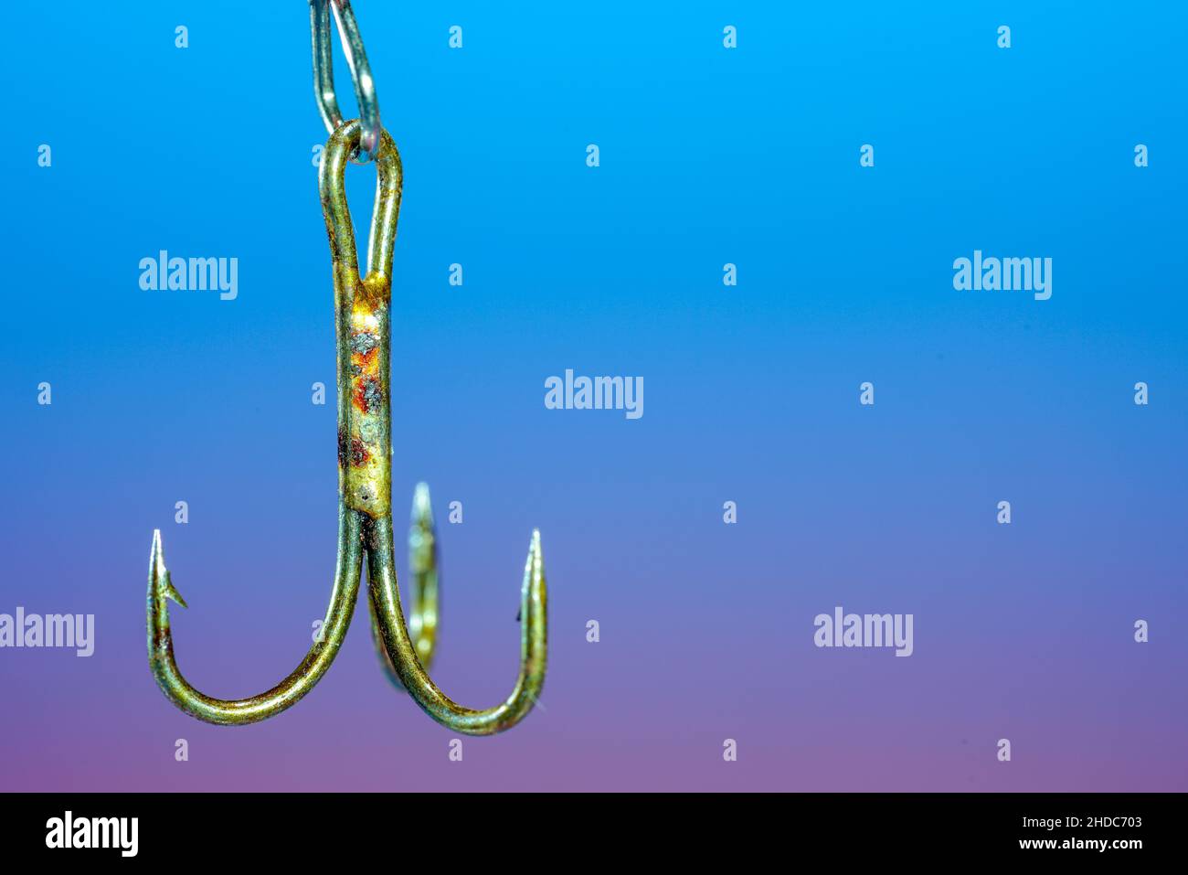 Nahaufnahme eines Angelhakens aus Metall mit einem Hintergrund in blau-violetter Farbe Stockfoto