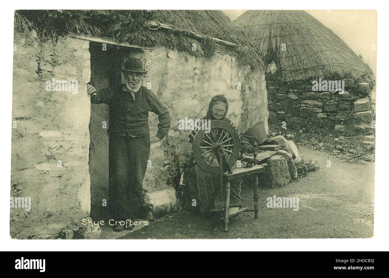 Ursprüngliche Postkarte aus der Edwardianischen Ära des frühen 20. Jahrhunderts von Skye-Croftern, Pächtern, außerhalb ihrer Croft hat die alte Frau ein Spinnrad und spinnt Wolle - Lebensunterhalt. Gedruckt von der zuverlässigen Serie von W R & S William Ritchie and Sons - um 1905. Isle of Skye, Innere Hebriden, Schottland, Großbritannien Stockfoto