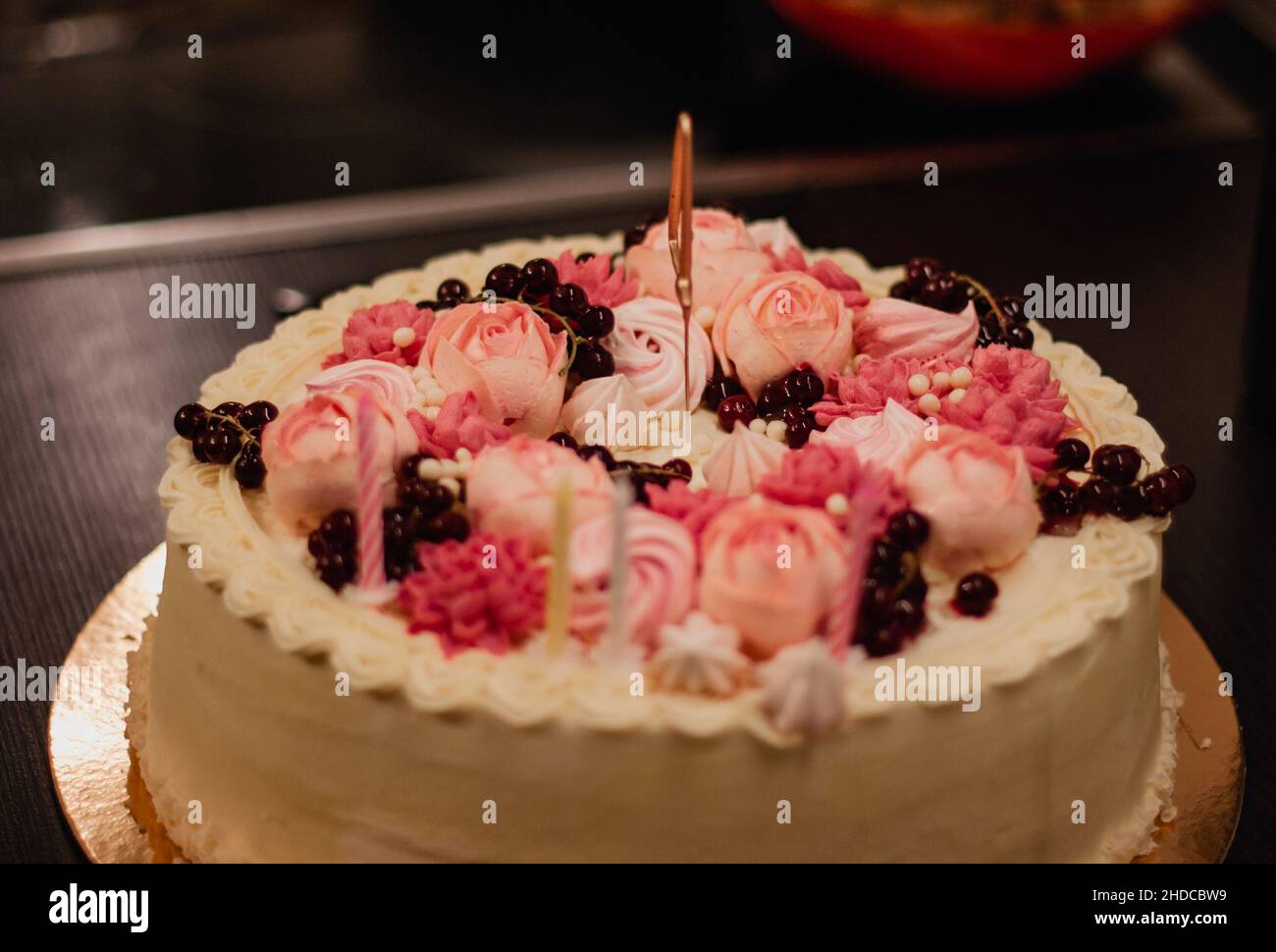 Geburtstagskuchen mit rosa Schlagsahne Blumen und Kerzen. Stockfoto