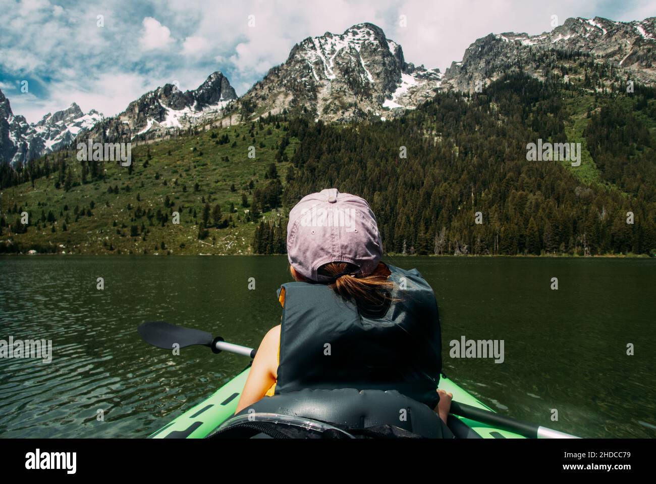 Junges Mädchen, das im See in der Nähe des verschneiten Berges Kajak fahren kann Stockfoto