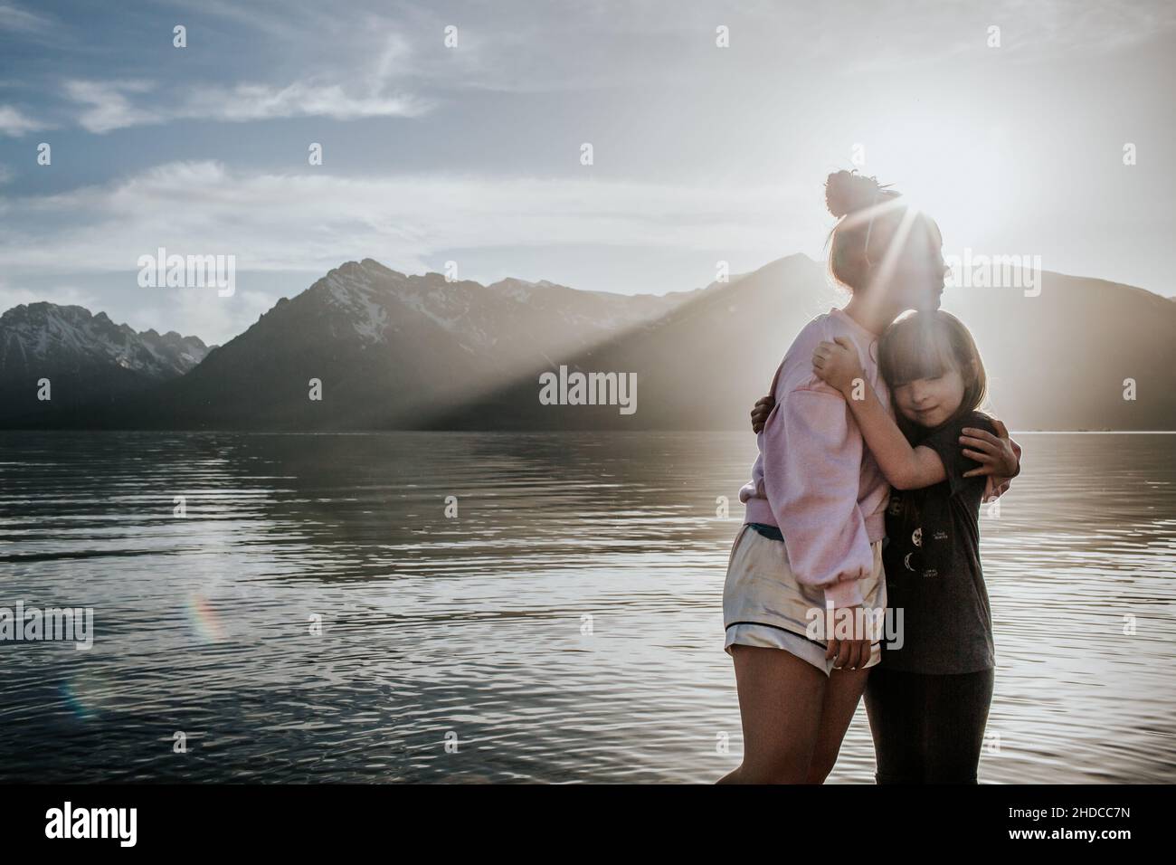Schwestern umarmen sich an einem sonnigen Tag in der Nähe des Bergsees Stockfoto