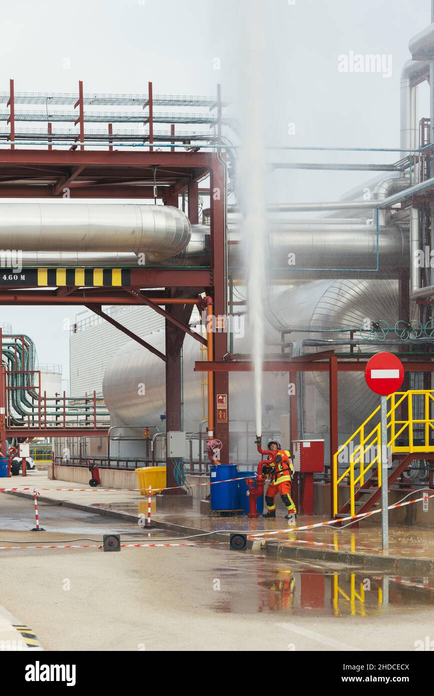 Feuerwehrmann wirft Wasser während einer Bohrmaschine in einer Fabrik. Stockfoto