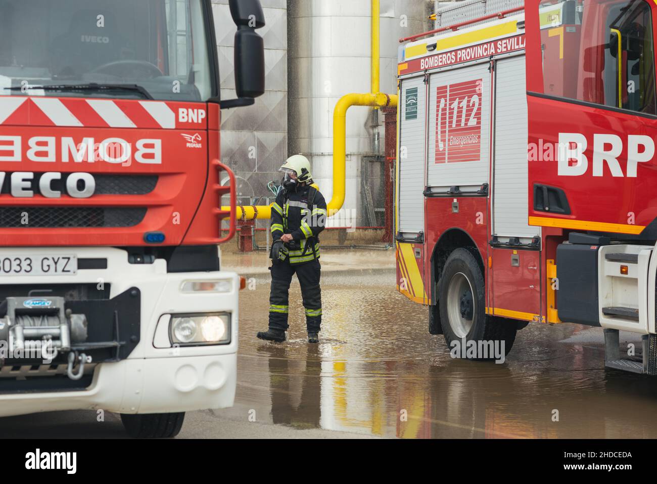 Feuerwehrmann, der während eines Trainings nachdenklich zwischen Lastwagen läuft. Stockfoto