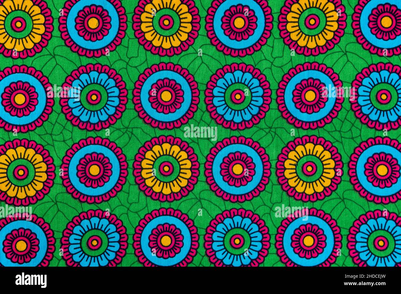 Bunte afrikanische bedruckte Textil-Nahaufnahme. Ethnisches geometrisches Muster, Stoff aus Tansania mit abstraktem Blumenmotiv und lebendigen Farben. Stockfoto Bunte afrikanische bedruckte Textil-Nahaufnahme. Ethnisches geometrisches Muster, Stoff aus Tansania mit abstraktem Blumenmotiv und lebendigen Farben. Stockfoto