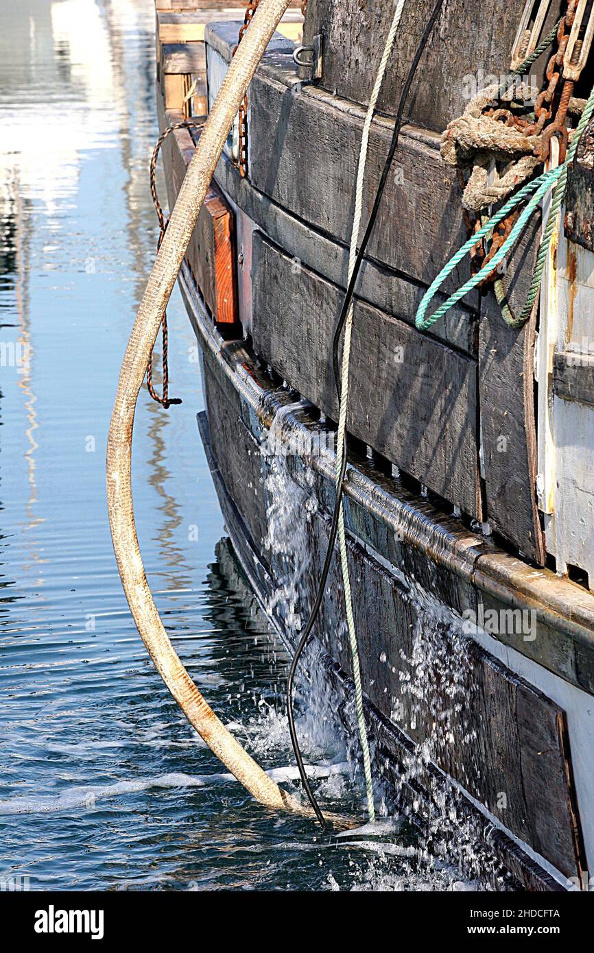 Seite des alten Holzbootes im Hafen, das Wasser freigibt Stockfoto