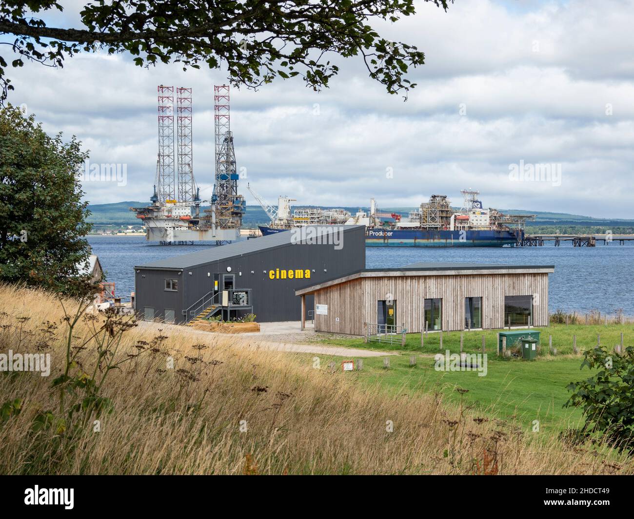The Cinema and Cromarty Links Hub Buildings with Oil Platform and ship behind. Cromarty, Black Isle, Highland, Schottland Stockfoto