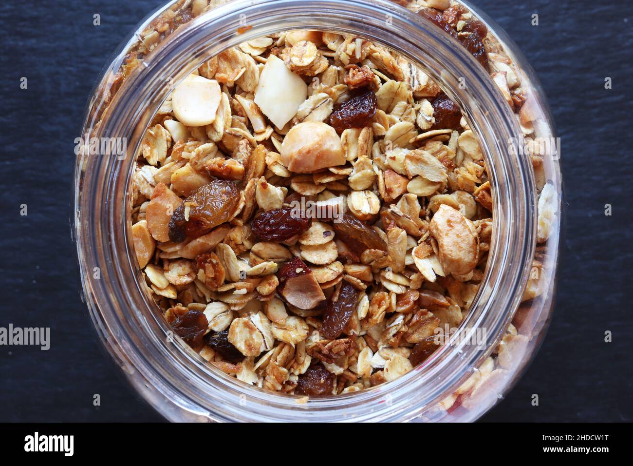 Fotografie von Granola in einem Glas auf Schiefer Hintergrund Lebensmittel Illustration Stockfoto