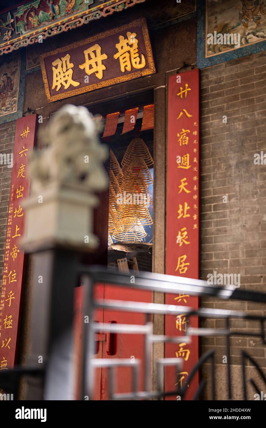 Shallow Focus Aufnahme einer Statue eines chinesischen Schutzlöwen mit einem verschwommenen chinesischen Tempelhintergrund Stockfoto