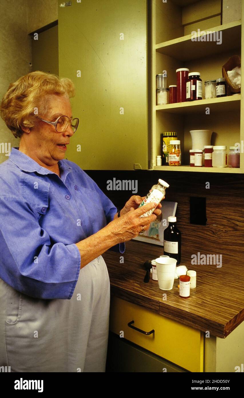 Austin Texas USA, 1987: Senioren sind vorsichtig bei der Einnahme von Medikamenten, schauen sich die Etiketten von verschreibungspflichtigen Flaschen genau an. Stockfoto