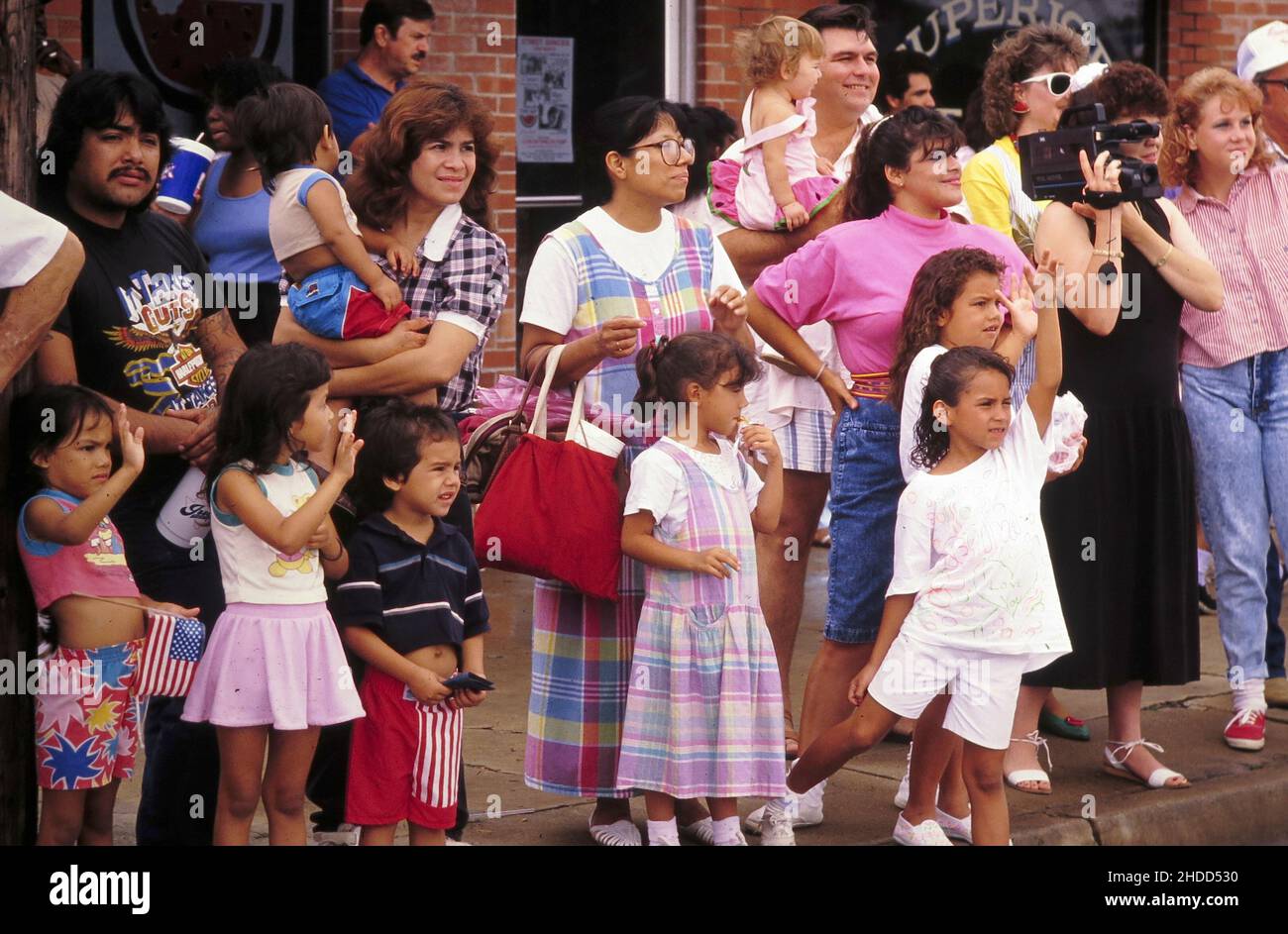 Luling Texas USA, 1990: Kinder und Eltern stehen auf dem Bürgersteig in der Innenstadt, während sie die jährliche Luling Watermelon Thump Parade vorbeiziehen sehen. ©Bob Daemmrich Stockfoto