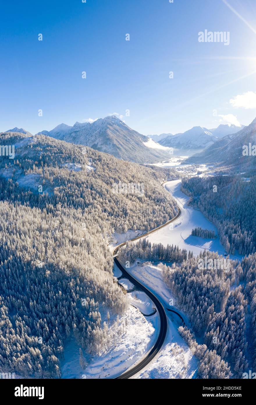 Vertikales Winterbild mit Straße zum Dorf heiterwang in tirol mit bewaldeten Bergen und viel Schnee Stockfoto