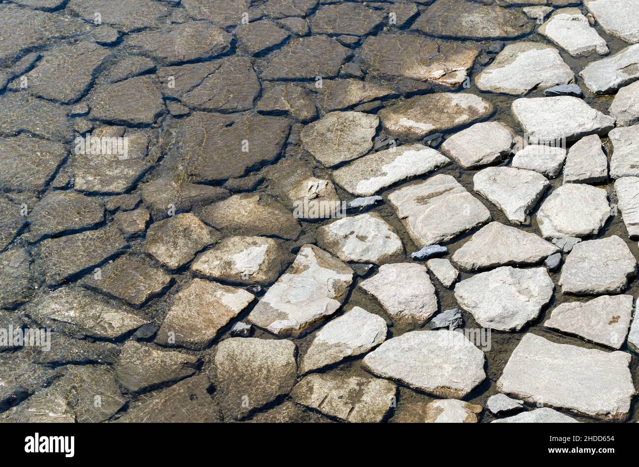 Textur, die durch die feuchten Felsen des Flussbetts hergestellt wird Stockfoto