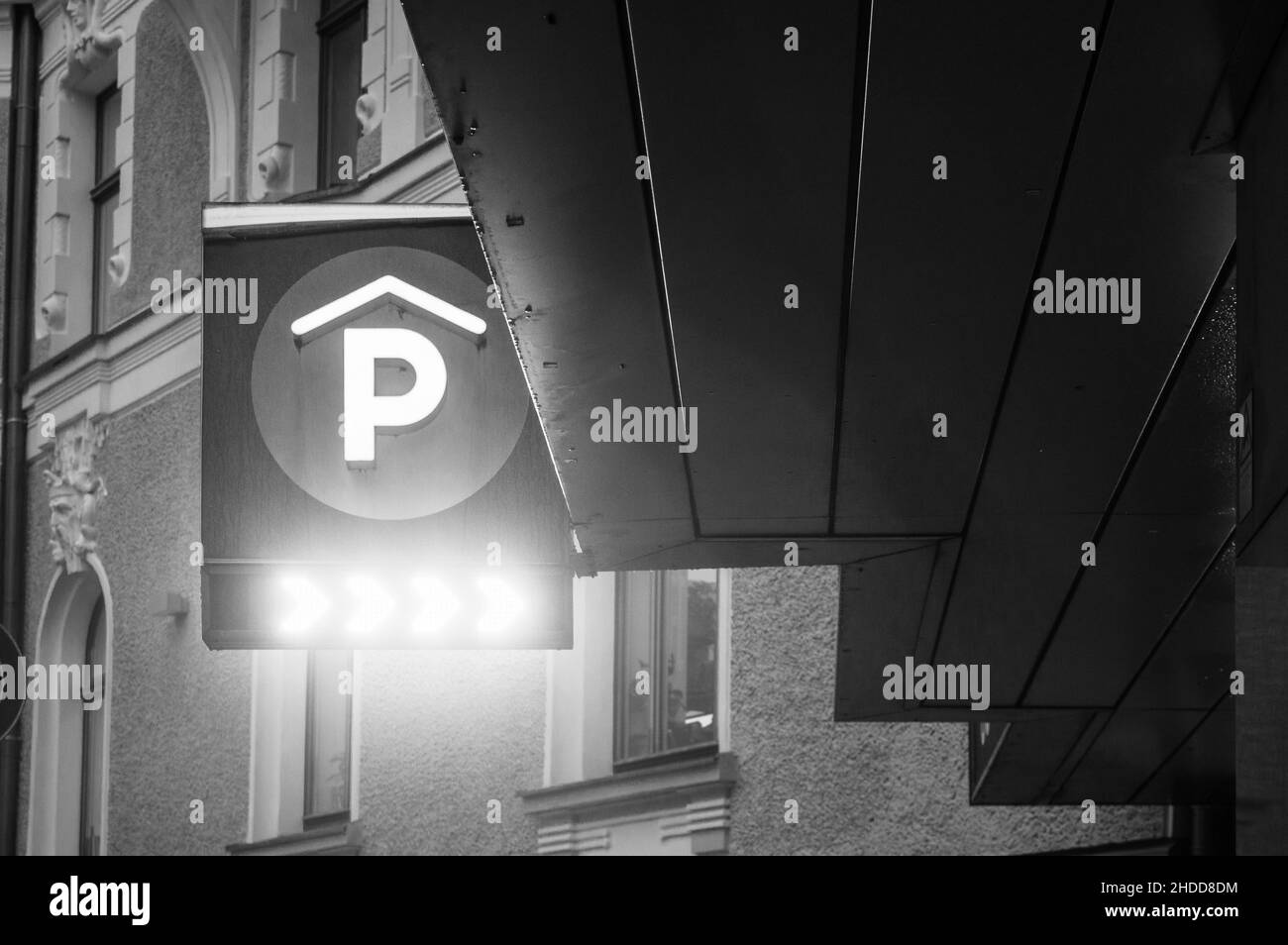Riga, Lettland, 4. Januar 2022: Stadtansicht des Parkplatzes mit P und Neonlicht-Richtungsschild Stockfoto