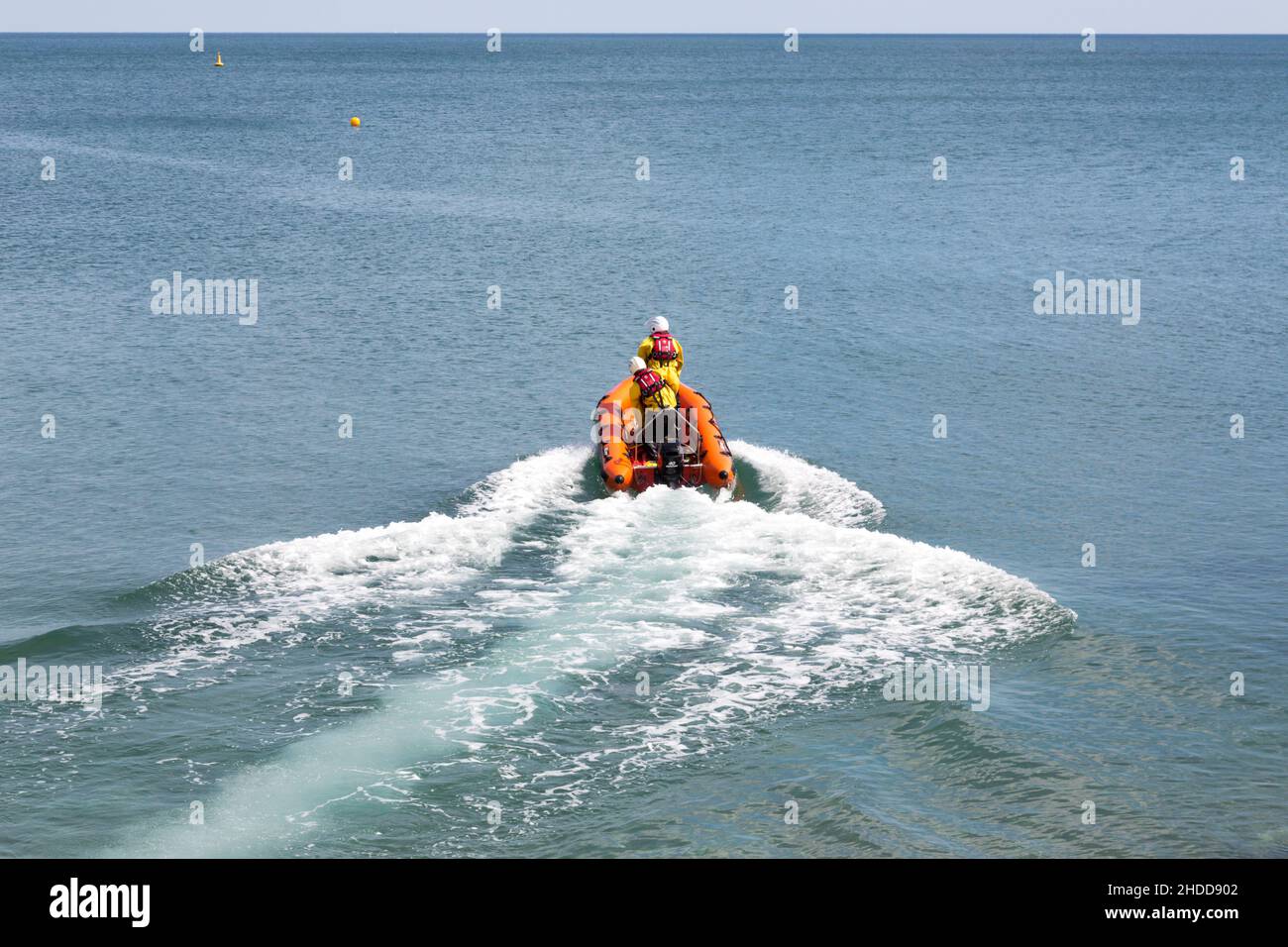 Ein aufblasbares Küstenrettungsboot, das vom Strand in Sidmouth Devon, England, zu einer Rettungsmission aufbricht. Besetzt mit zwei Besatzungen, die auf dem Weg auf See sind Stockfoto