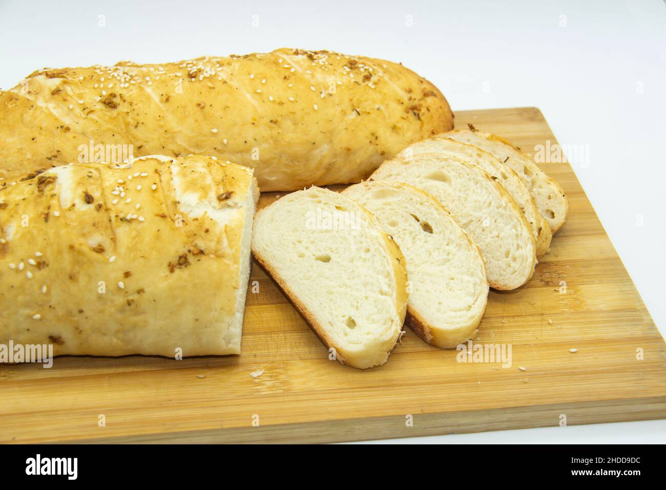 Weizenbrot aus Mehl zu Hause gebacken. Brotscheiben auf Holzbrett vor Hintergrund. Lebensmittel ohne GVO. Hausgemachtes Brot mit Gewürzen darauf. Stockfoto