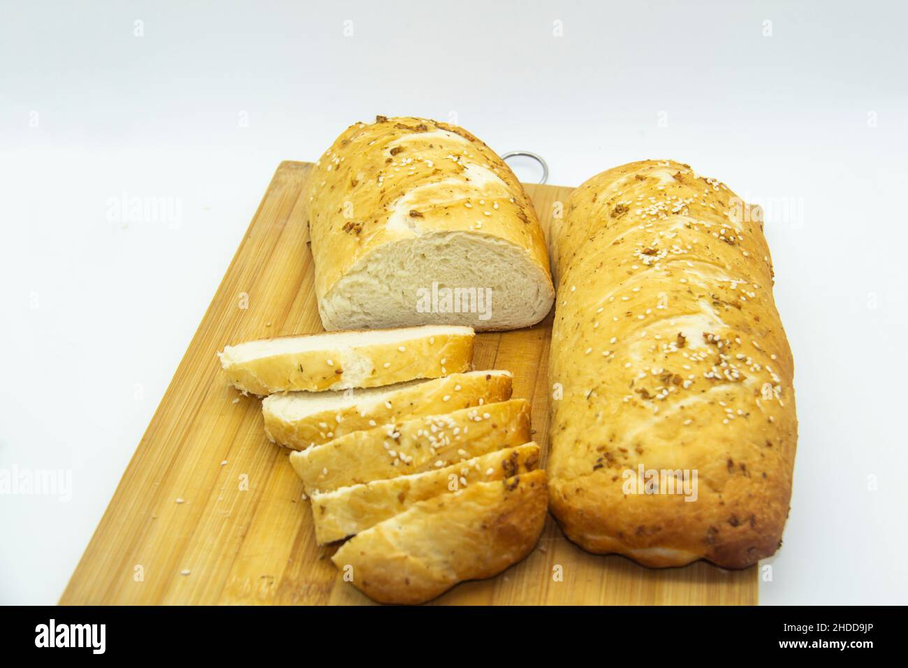 Weizenbrot aus Mehl zu Hause gebacken. Brotscheiben auf Holzbrett vor Hintergrund. Lebensmittel ohne GVO. Hausgemachtes Brot mit Gewürzen darauf. Stockfoto