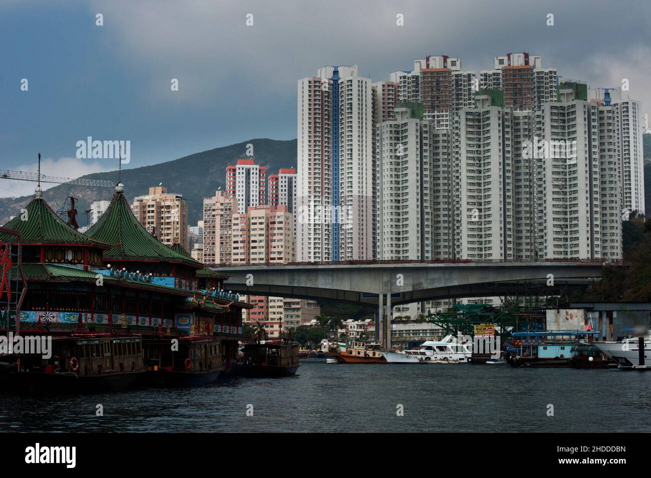 Jumbo Kingdom, ein schwimmendes Restaurant, mit der Kulisse des Aberdeen Floating Village und den Turmblöcken dahinter, Hongkong. Stockfoto