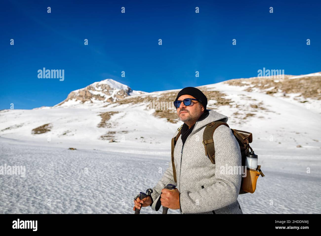 Ein Mann geht allein auf dem Schnee in den Bergen, auf den Gipfel, an einem sonnigen Wintertag. Sportliche Menschen im Schnee. Stockfoto