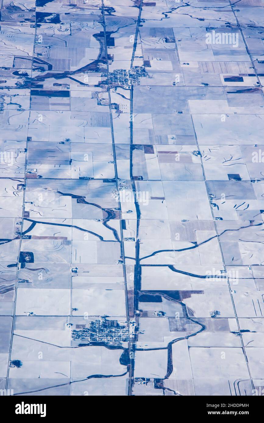 Luftaufnahme von kleinen Städten, die in Iowa im Winter von gefrorenem Ackerland umgeben sind. Stockfoto