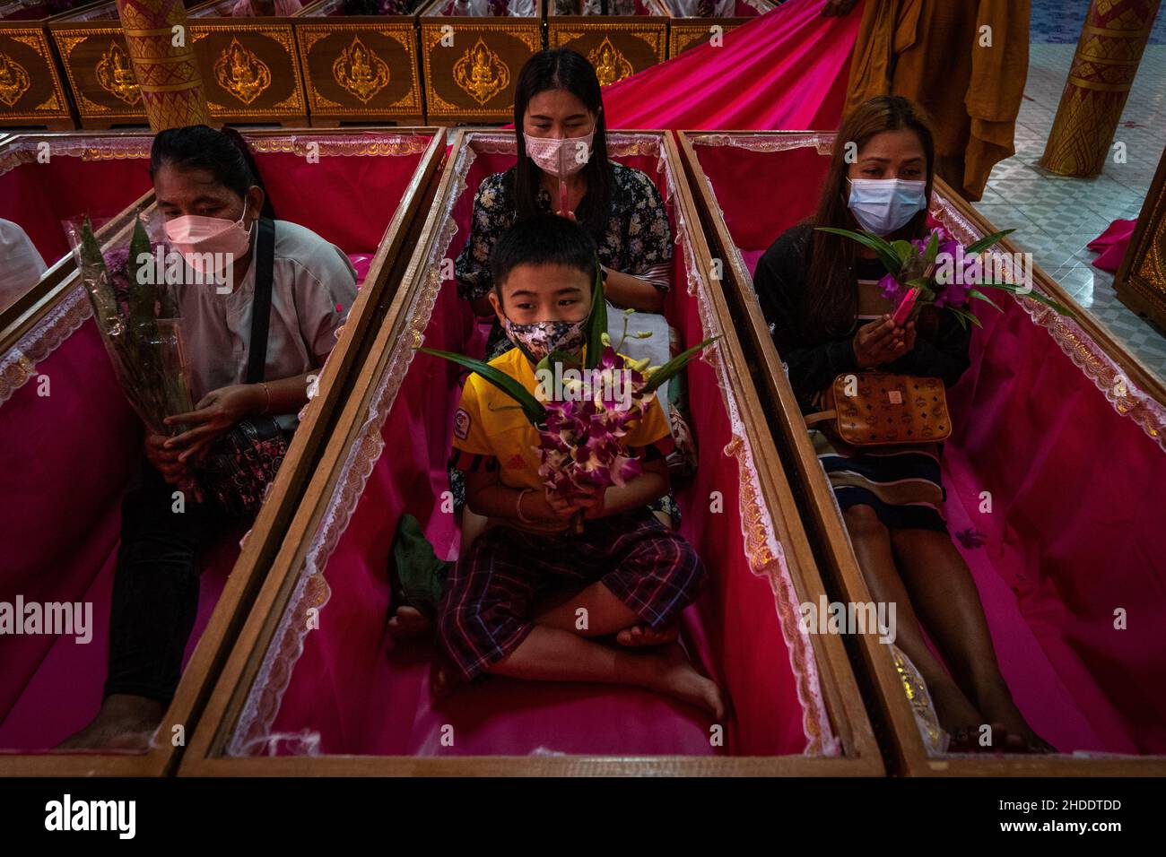 Bangkok, Thailand. 31st Dez 2021. Die thailändische Familie wird als Teil des Auferstehungsrituals im Tempel in Särgen sitzend gesehen.Devotees werden in einem jährlichen Neujahrsritual im Wat Takien in der Nähe von Nonthaburi wiederbelebt. Dieser Ritus beginnt mit einem Gebet, gefolgt von den Teilnehmern, die mit heiligen Fäden um ihren Kopf gewickelt singen, bevor sie sich in einen Sarg legen, um zu „sterben“ und gereinigt zu werden. (Foto von Matt Hunt/SOPA Images/Sipa USA) Quelle: SIPA USA/Alamy Live News Stockfoto