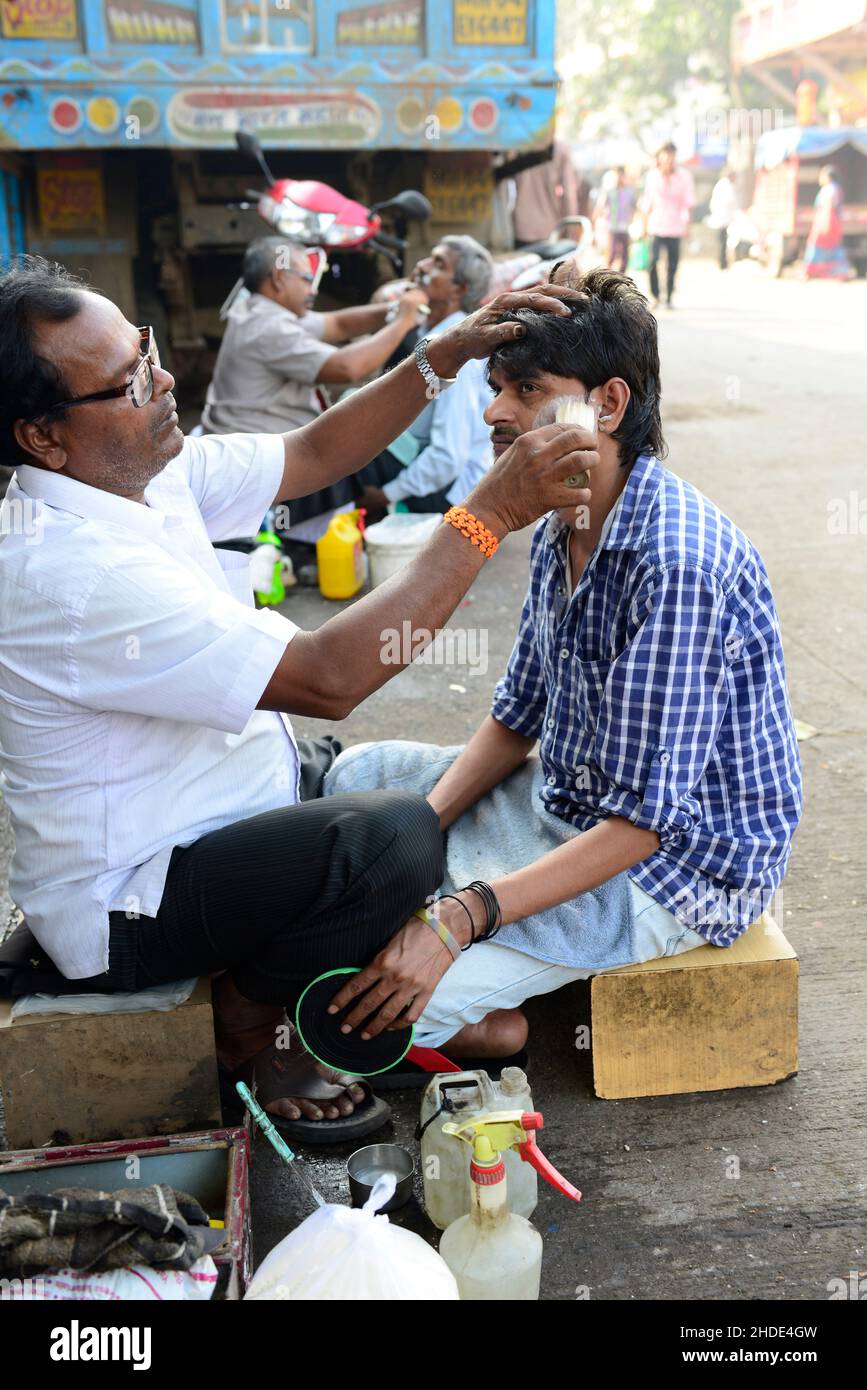 Ein Straßenbarbier, der seinen Kunden in Mumbai, Indien, rasiert. Stockfoto