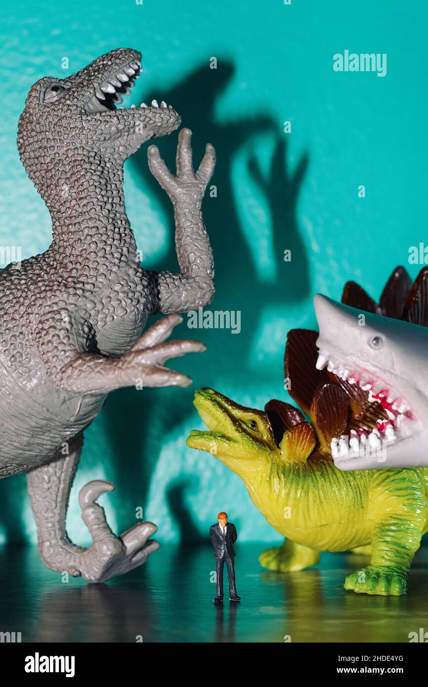 Spielzeug Dinosaurier und Haie Mobbing und lachend über armen traurigen Geschäftsmann Stockfoto