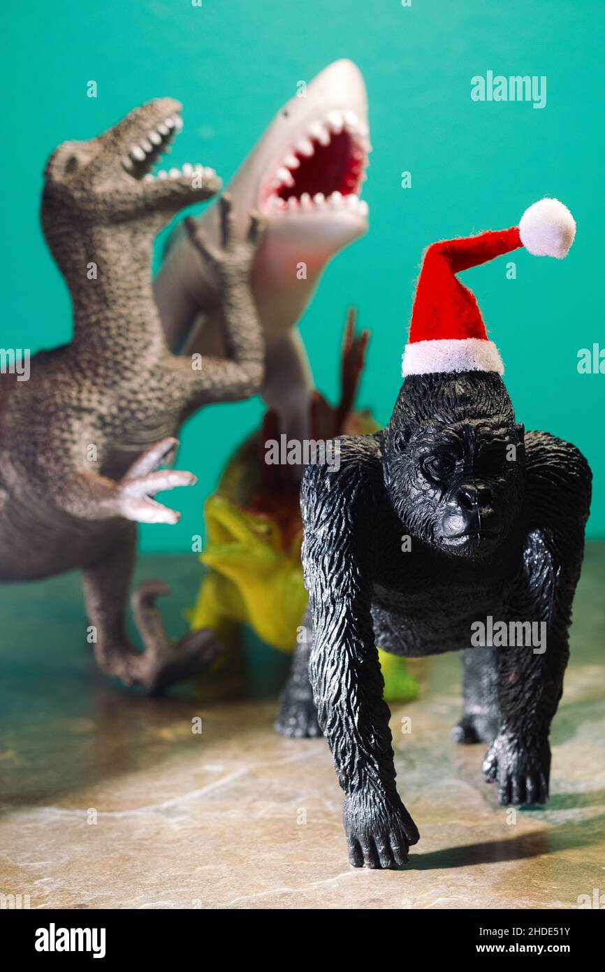 Uneingeladen zu Weihnachten hysterisch lachende Schläger verspotten traurigen Gorilla, der Santa Hut als Metapher trägt Stockfoto